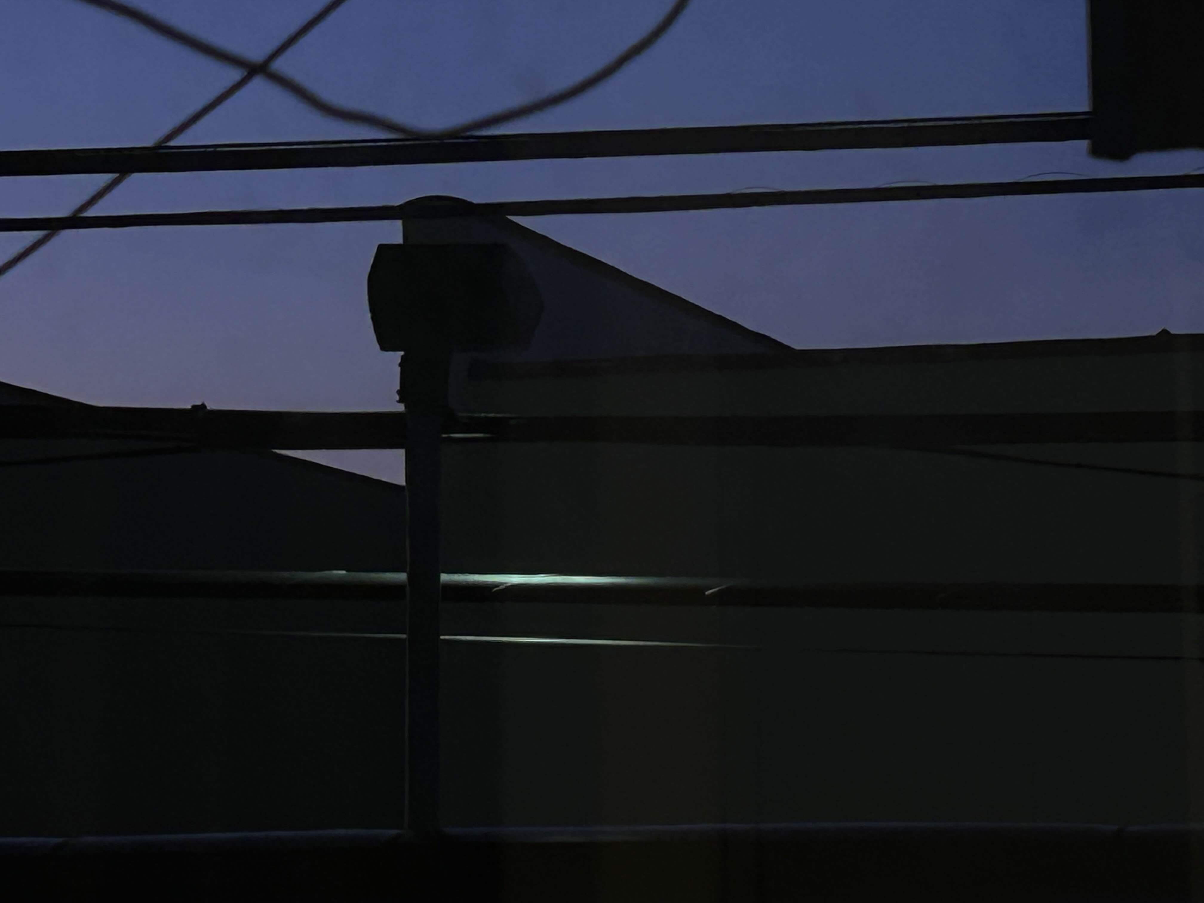 a lamp under a night sky shines the only illumination onto a power line